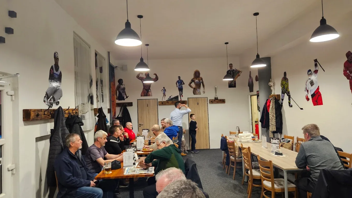 Hosté u stolů a sportovní výzdoba v interiéru Sport Pubu